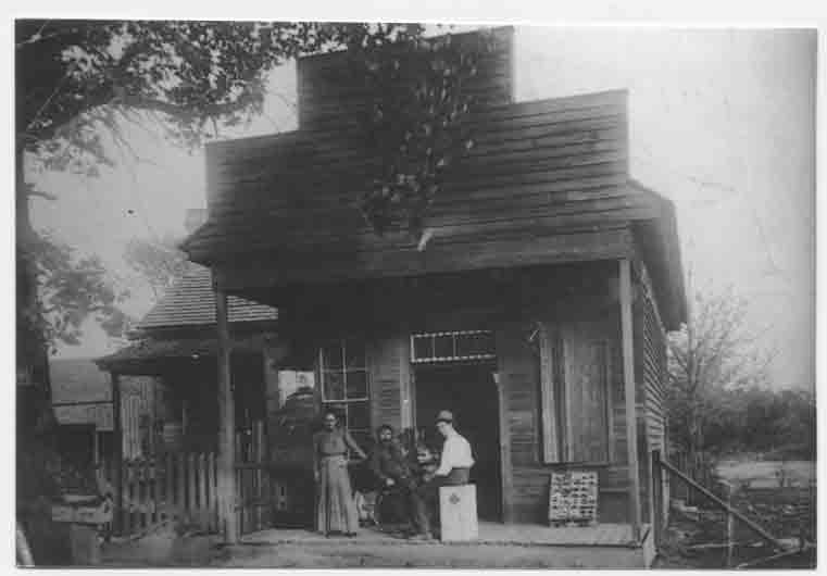 This is a picture of my great grandparents, Robert Wiley Carter and Malinda Bell Leonard Carter.  Robert is in a wheelchair, having suffered a stroke at age 44 and an unknown man is sitting on a box.  The picture was taken in front of a store run by my great-grandparents in Wesson abt 1915.